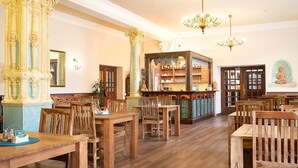 Eine großzügige Bibliothek mit Holztischen und -stühlen, verzierten Säulen und einem Bücherregal voller Bücher.