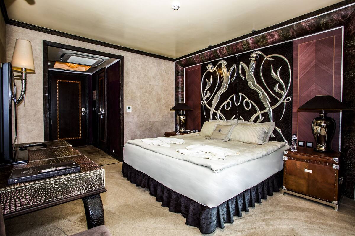 A bedroom with a large bed, a desk, and a wardrobe.