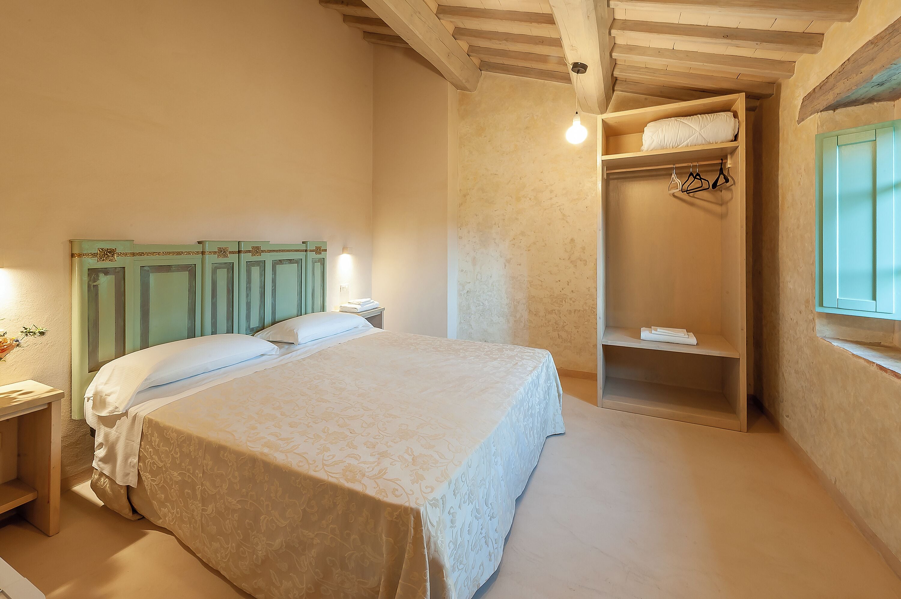 A bedroom with a bed, a wardrobe, and a window.