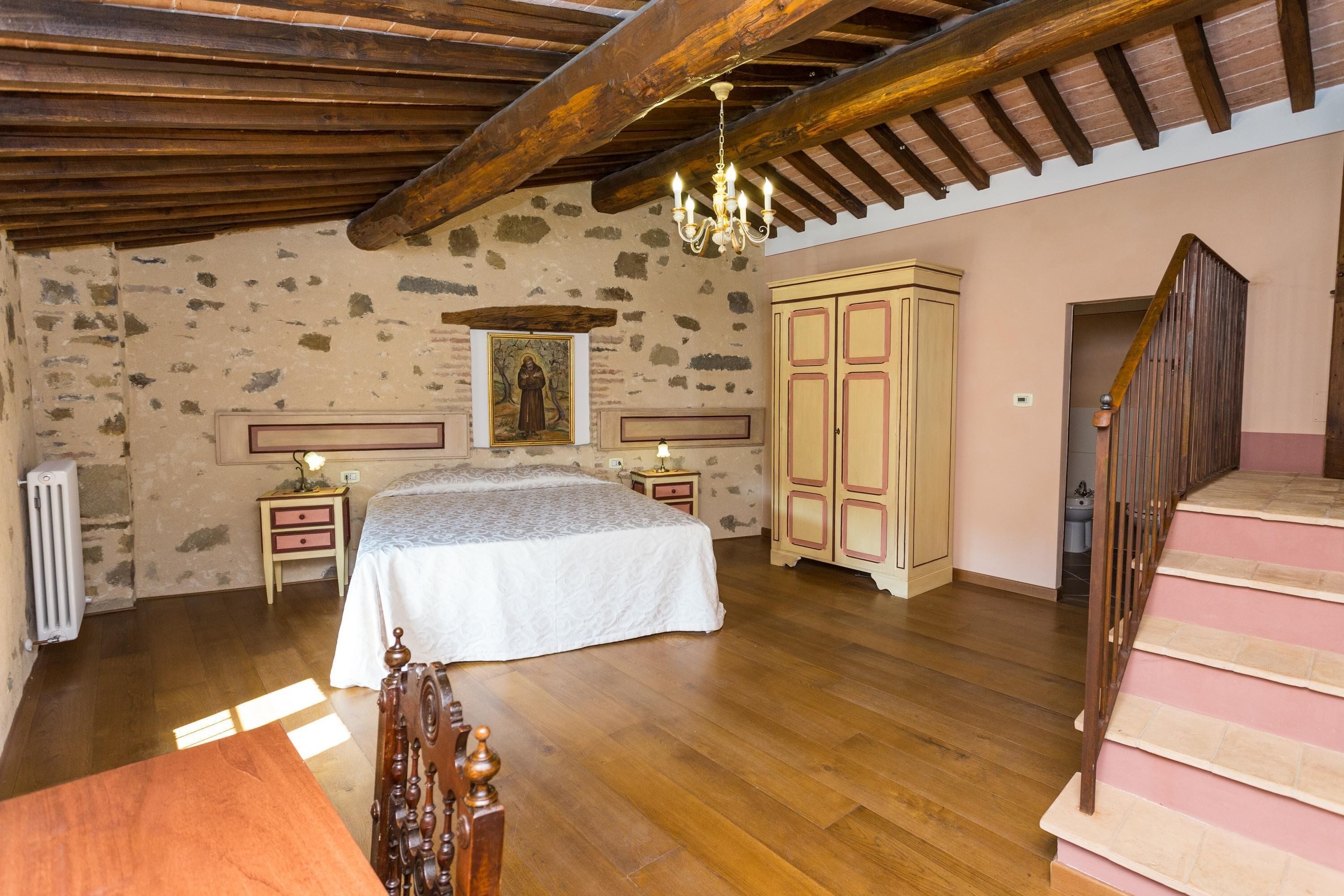 Un dormitorio con una cama de madera, una mesita de noche, un aparador y una escalera.