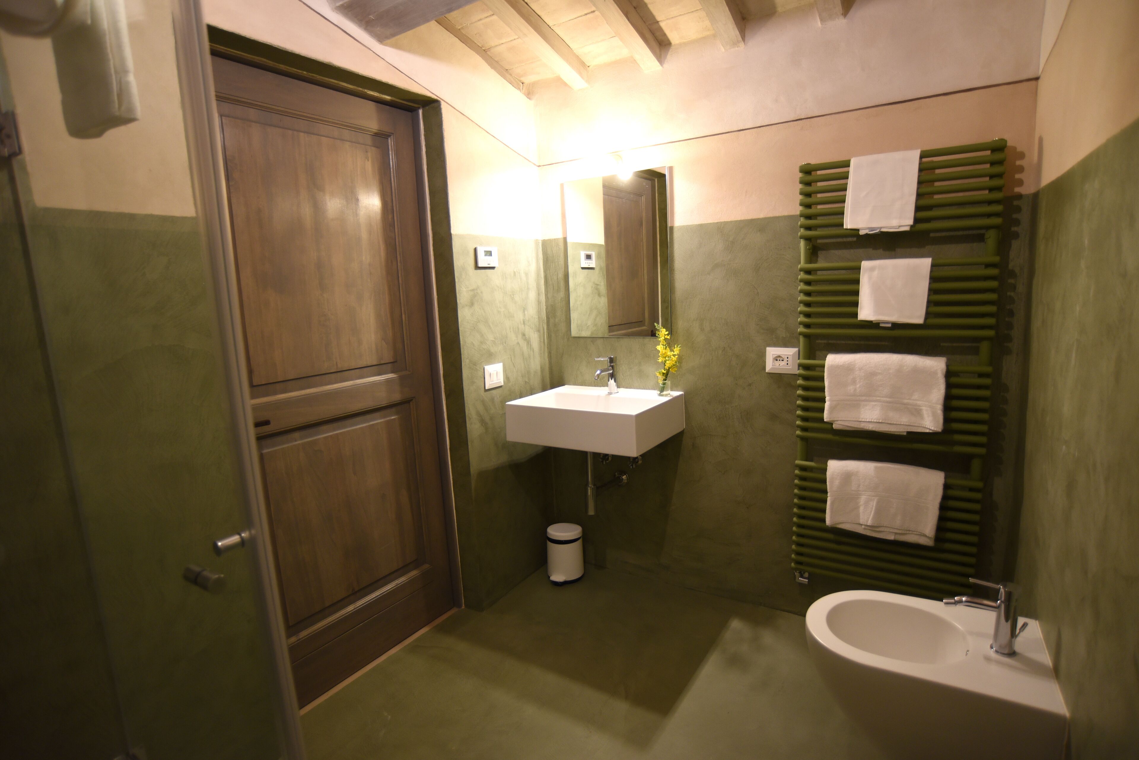 A bathroom with a wooden door, a white sink, a mirror, a towel rack, and a bathtub.