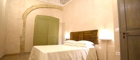 Une chambre à coucher avec un lit, une porte verte, un mur en pierre et un plafond en bois.