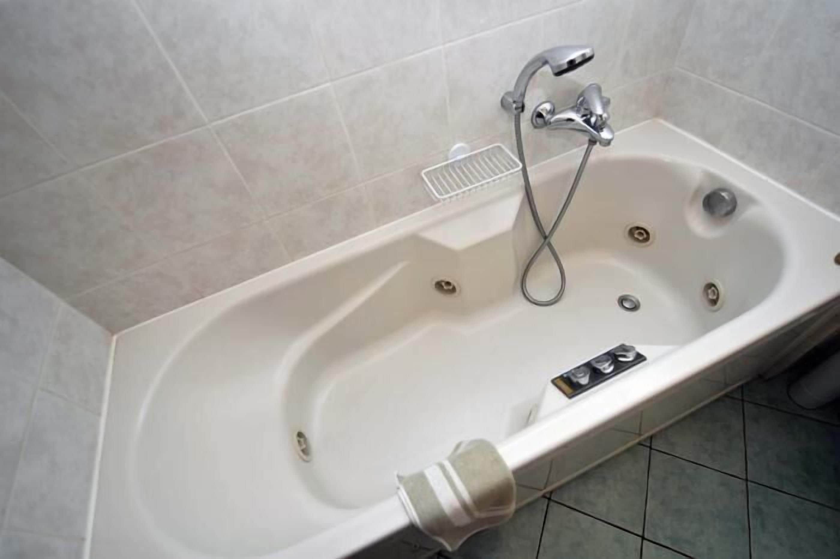 A modern bathroom with a freestanding bathtub, a handheld showerhead, and a built-in drain.