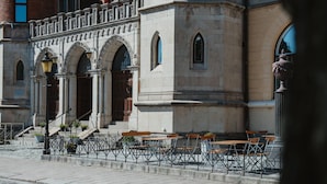 A building with arched windows, a stone facade, and outdoor seating with tables and chairs. - Home Hotel Borgen (Örebro)
