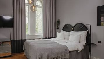 A modern bedroom with a bed, a bedside table, a TV, and a window with curtains.
