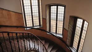 A spiral staircase with a handrail, leading to a landing with three arched windows. - Home Hotel Borgen (Örebro)