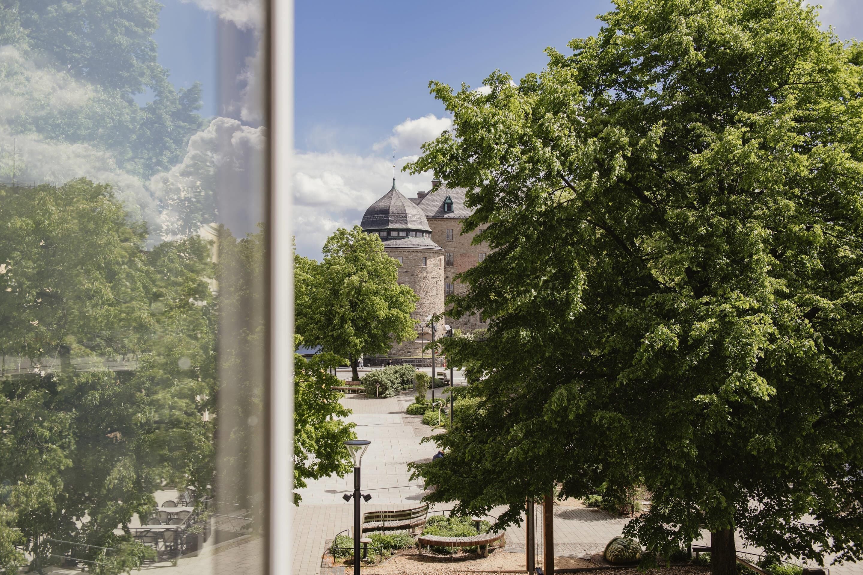 A view of a historic building with a dome, surrounded by trees and a paved walkway.