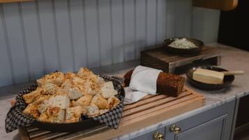 A kitchen counter with a bowl of bread, a wooden cutting board, and a bowl of onions.