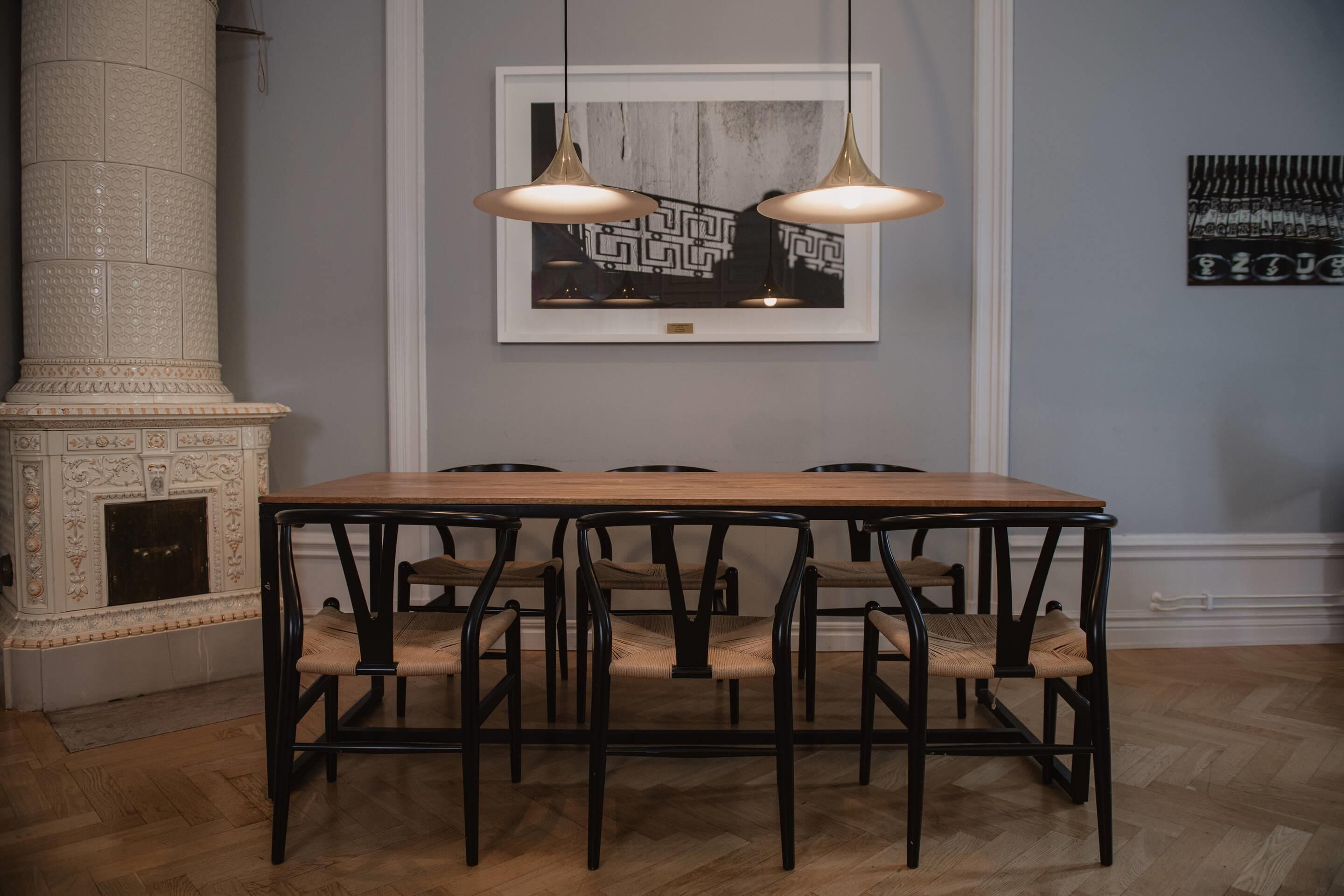 Un comedor con una mesa y sillas de madera, una chimenea y lámparas colgantes.