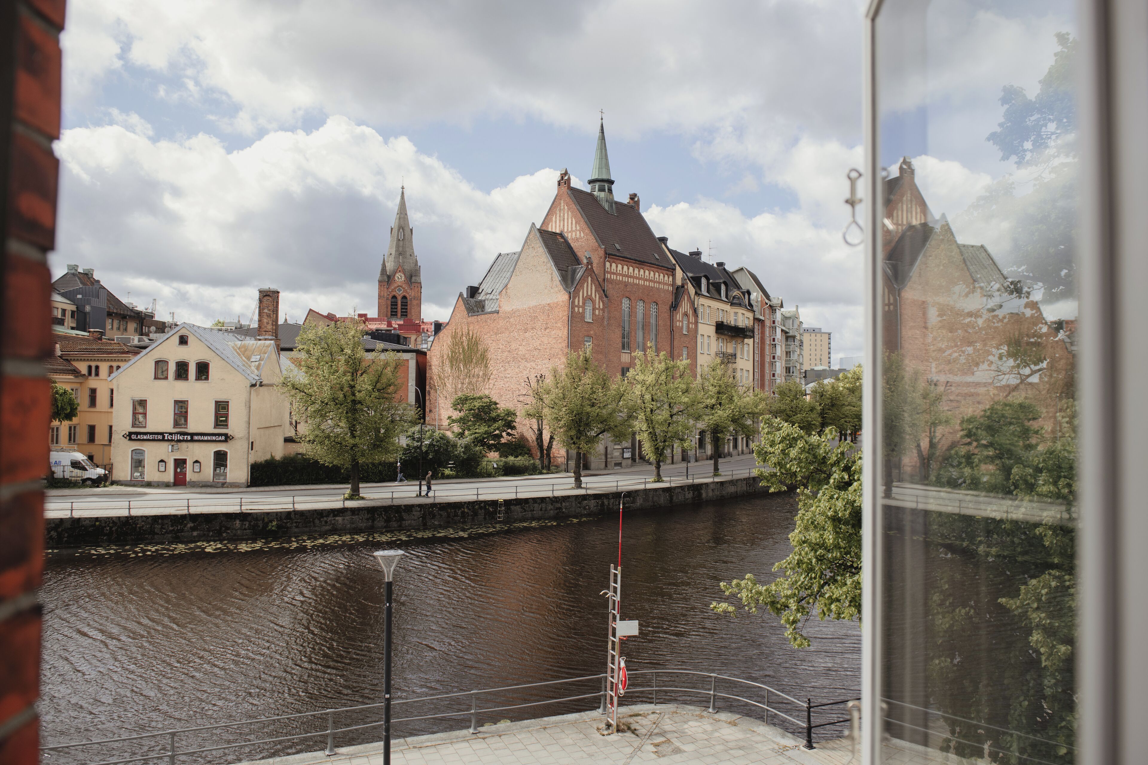 A riverside view of a historic building with a prominent tower and a brick facade.