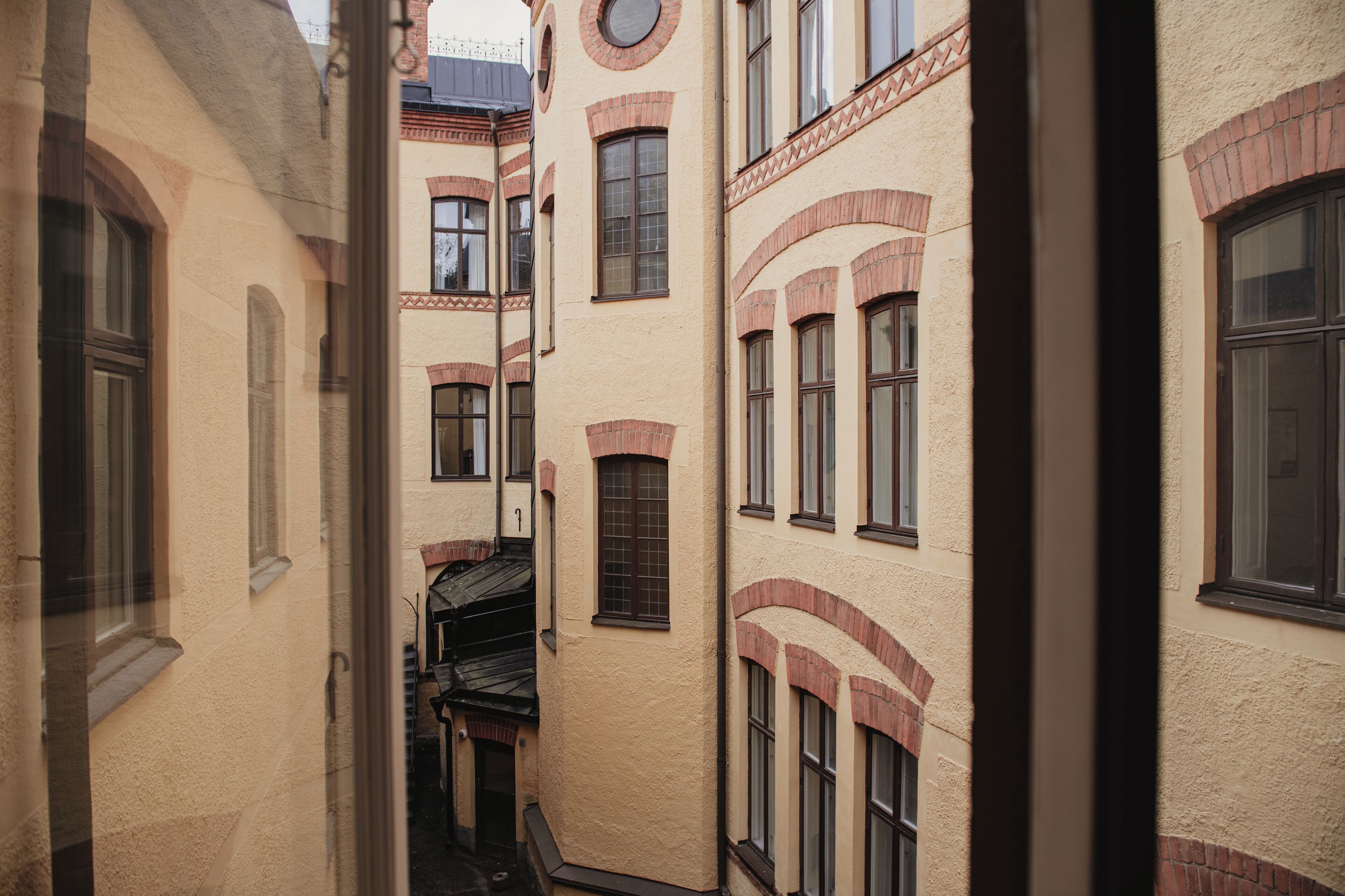 A narrow alleyway between buildings with arched windows and a small staircase leading to an upper level.
