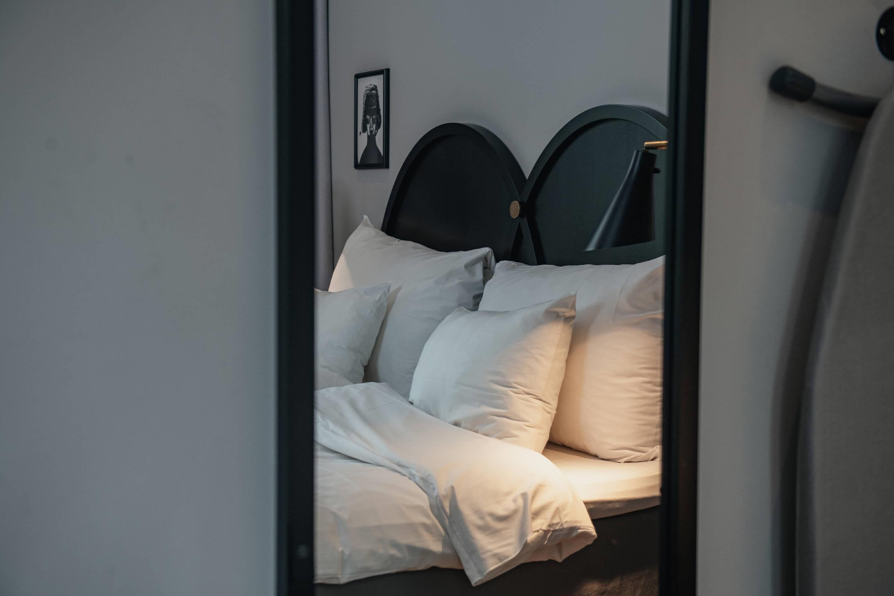 Cama com cabeceira, almofadas e um quadro fixado na parede.