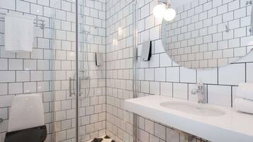 Een moderne badkamer met witte betegelde wanden, een glazen douchecabine, een wit wastafelmeubel en een vloer met een zwart-wit patroon.