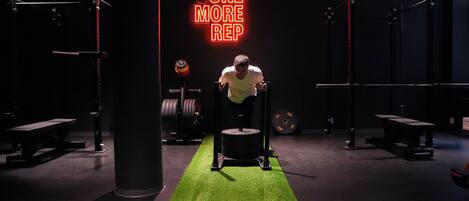 A gym with a neon sign reading "ONE MORE REP" and weightlifting equipment.