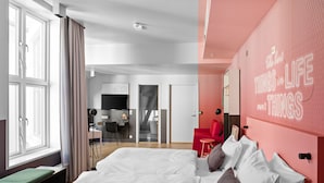 Een moderne hotelkamer met een groot bed, een bureau en een rode accentmuur.