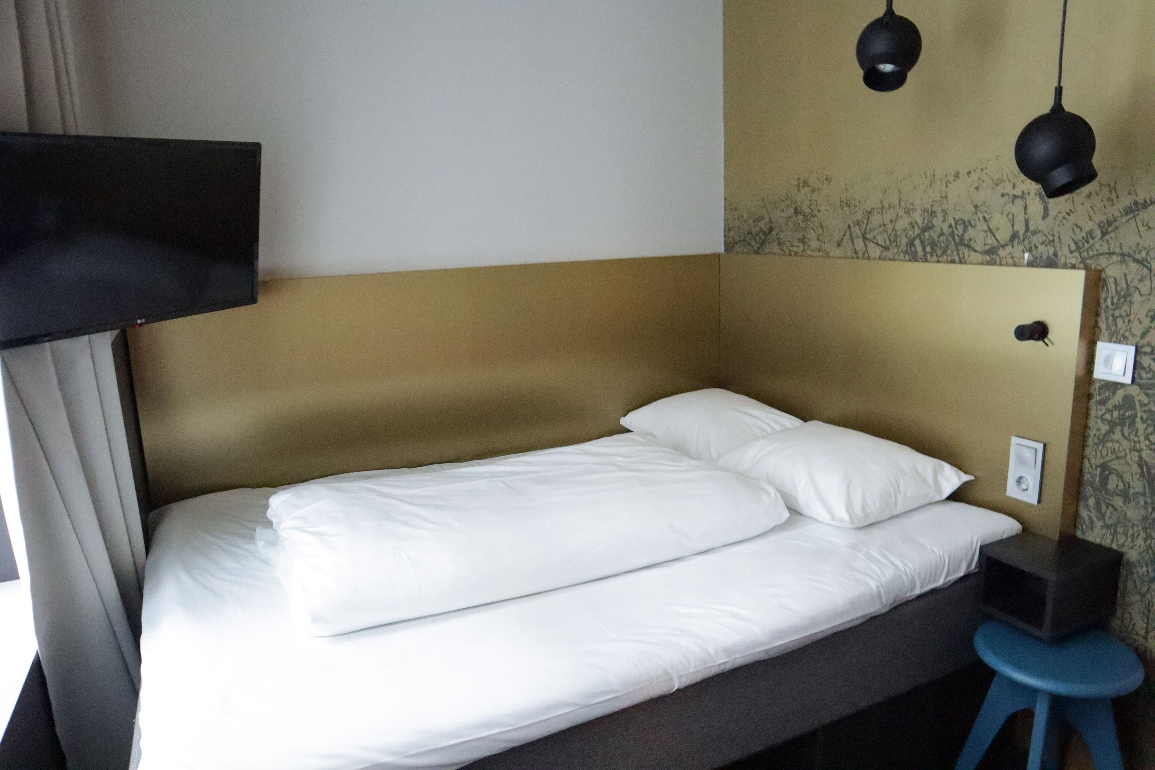Un lit bien fait, avec du linge de lit blanc, dans une chambre d’hôtel.