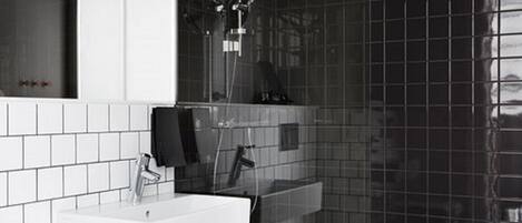 A modern bathroom with a white sink, a mirror, and a shower with a glass enclosure.