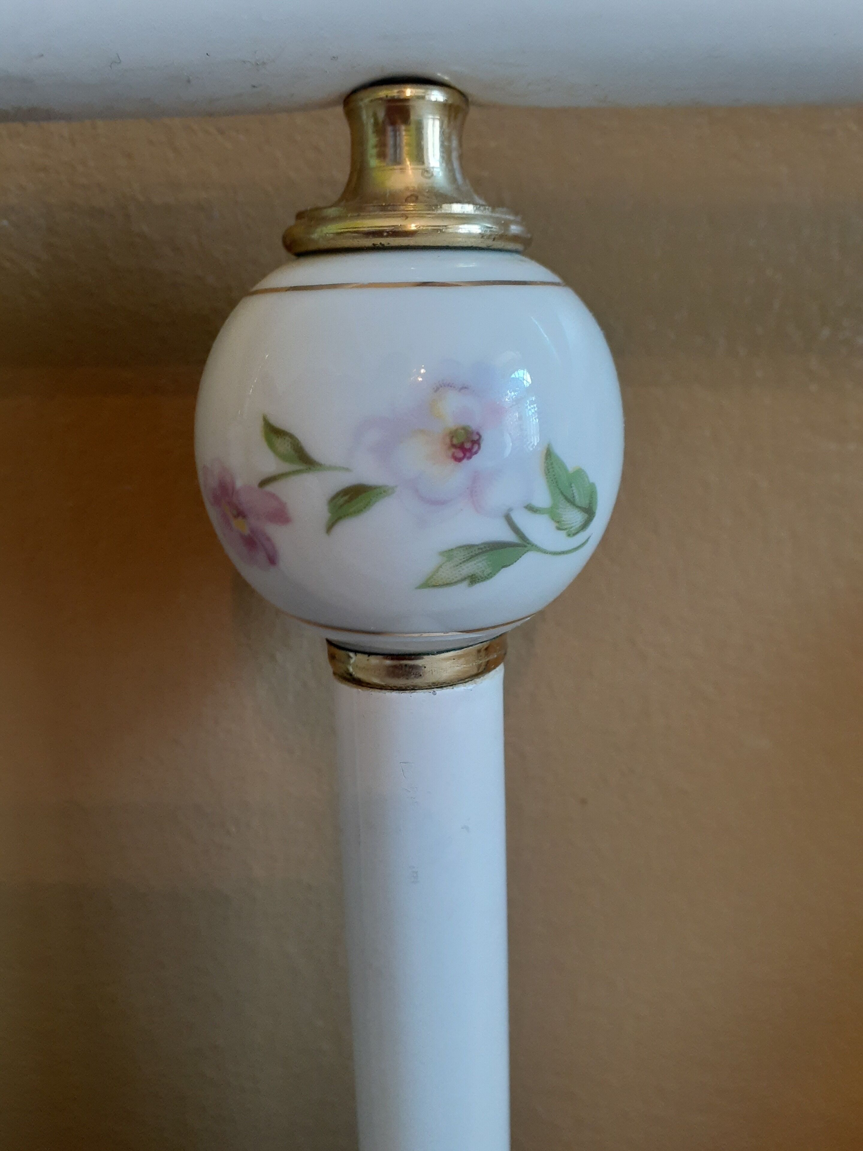 A white ceramic object with a gold top and floral design.