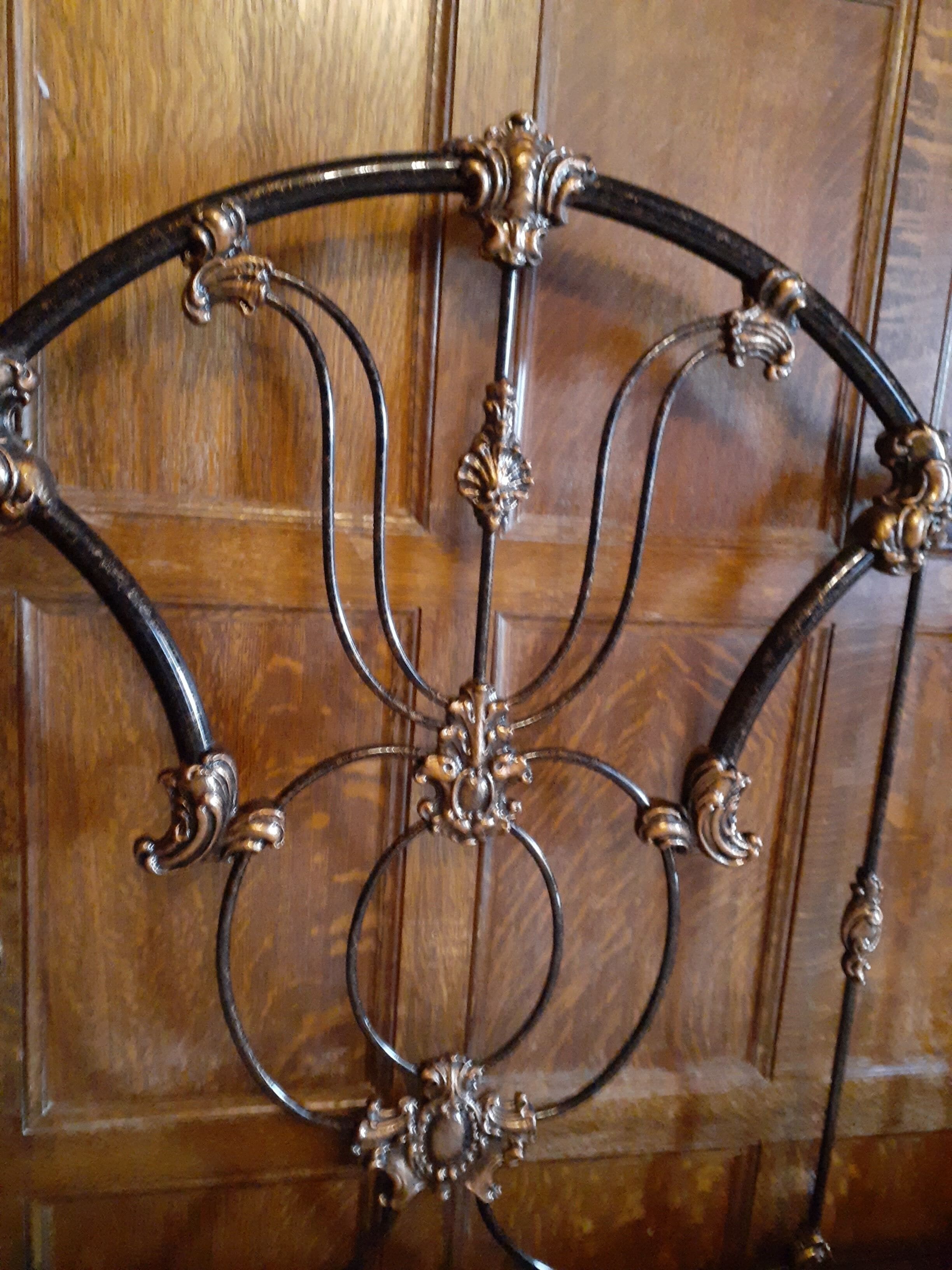 A wrought iron gate with intricate designs and a wooden background.