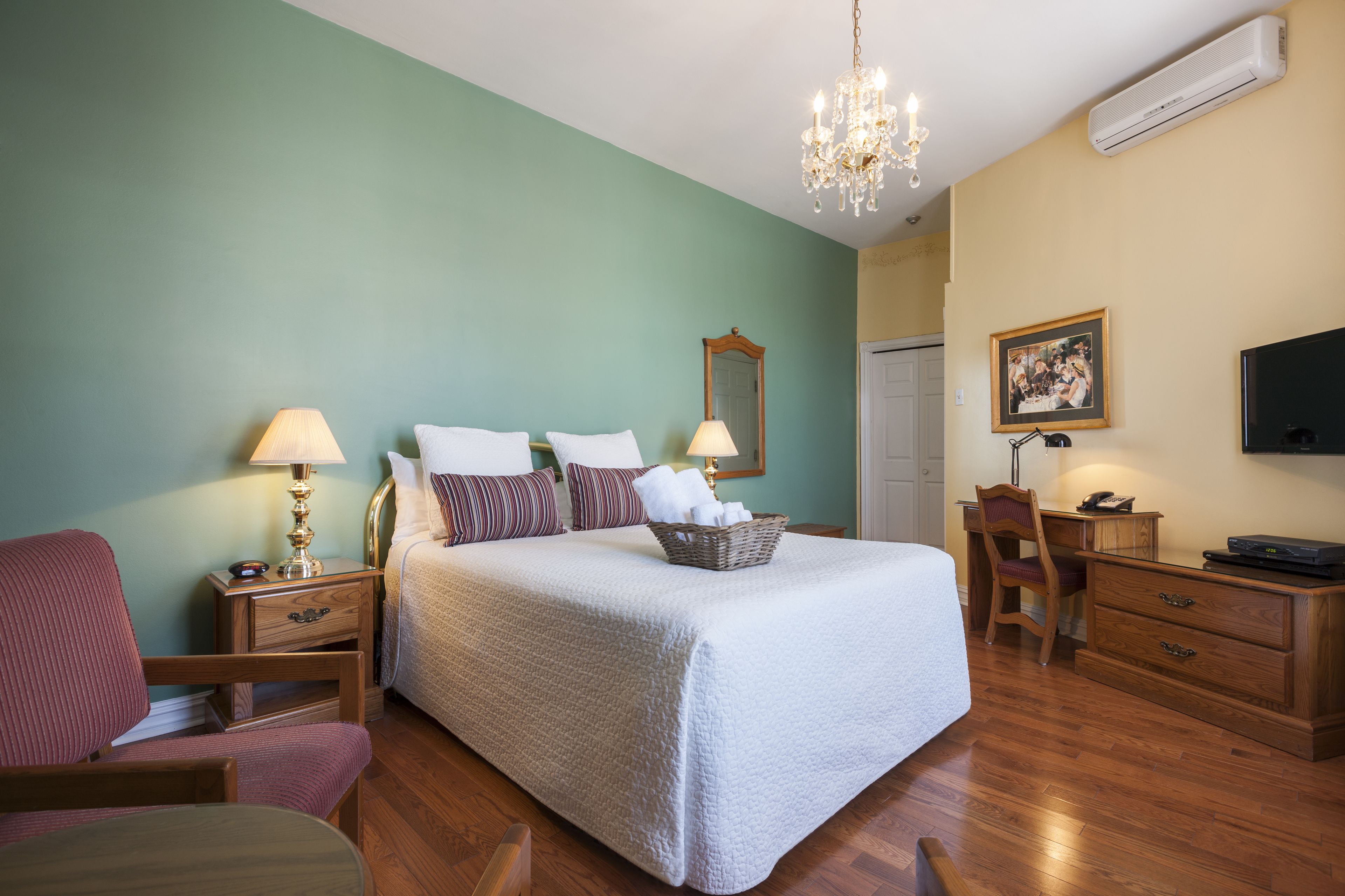 A bedroom with a bed, nightstands, a chair, a desk, and a television.