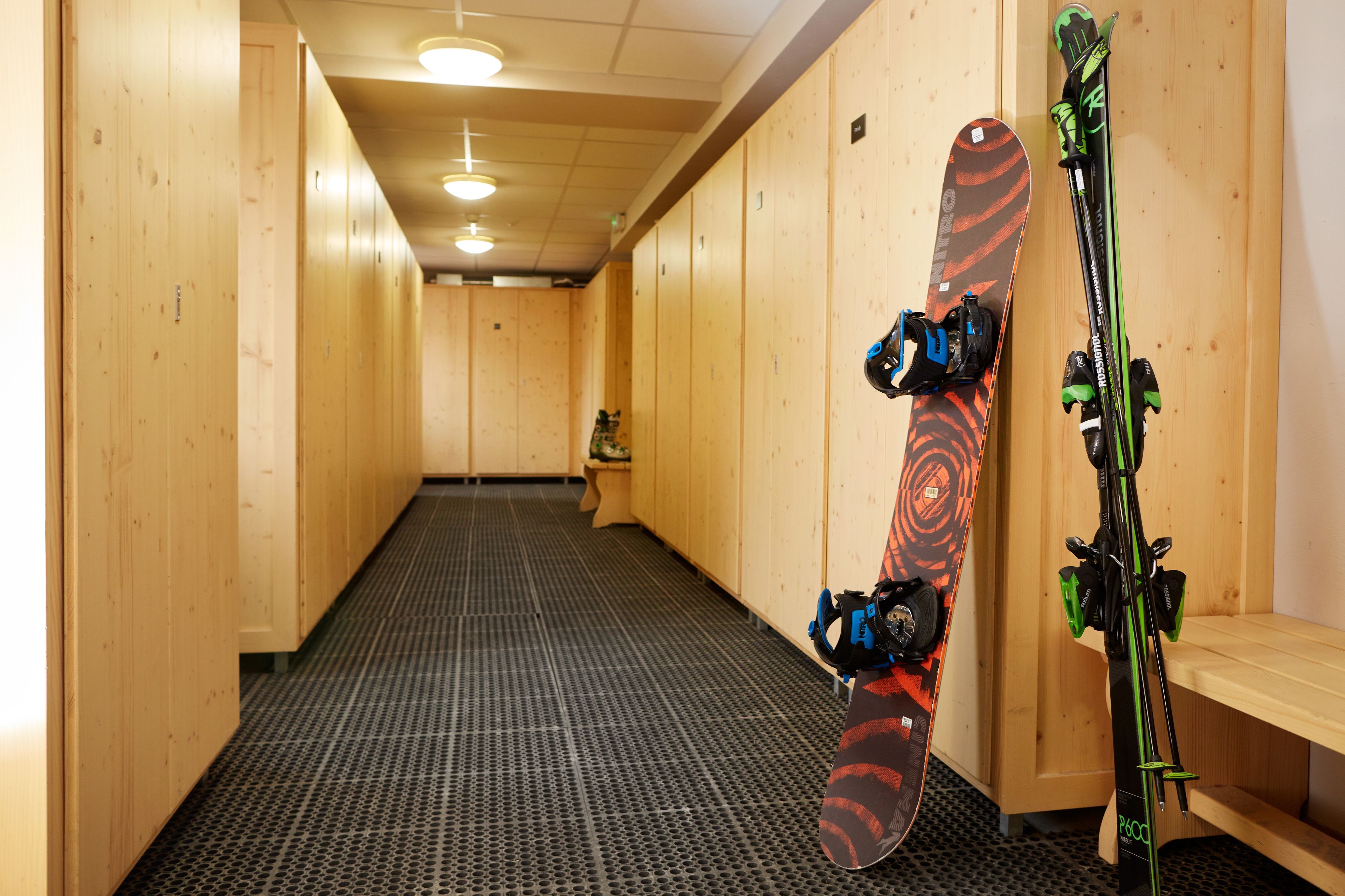 A hallway with lockers and a snowboard leaning against the wall.