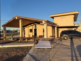 Un edificio con un letrero que dice 'Office', una zona de estacionamiento techada y una mesa al frente.