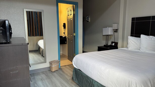 A hotel room with a bed, a desk, a mirror, and a bathroom visible through an open door. - Executive Inn Crystal City (Crystal City)