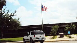 A white SUV parked in front of a building with an American flag. - Executive Inn Crystal City (Crystal City)