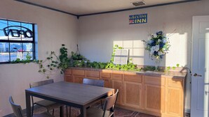 A hotel room with a wooden table and chairs, a window with a view of the street, a sign for Executive Inn, and a decorative plant arrangement. - Executive Inn Crystal City (Crystal City)