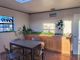 Una habitación de hotel con una mesa y sillas de madera, una ventana que da a la calle, un cartel de Executive Inn y un arreglo floral decorativo.