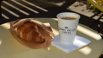 A croissant in a paper wrapper and a coffee cup with text on a table.