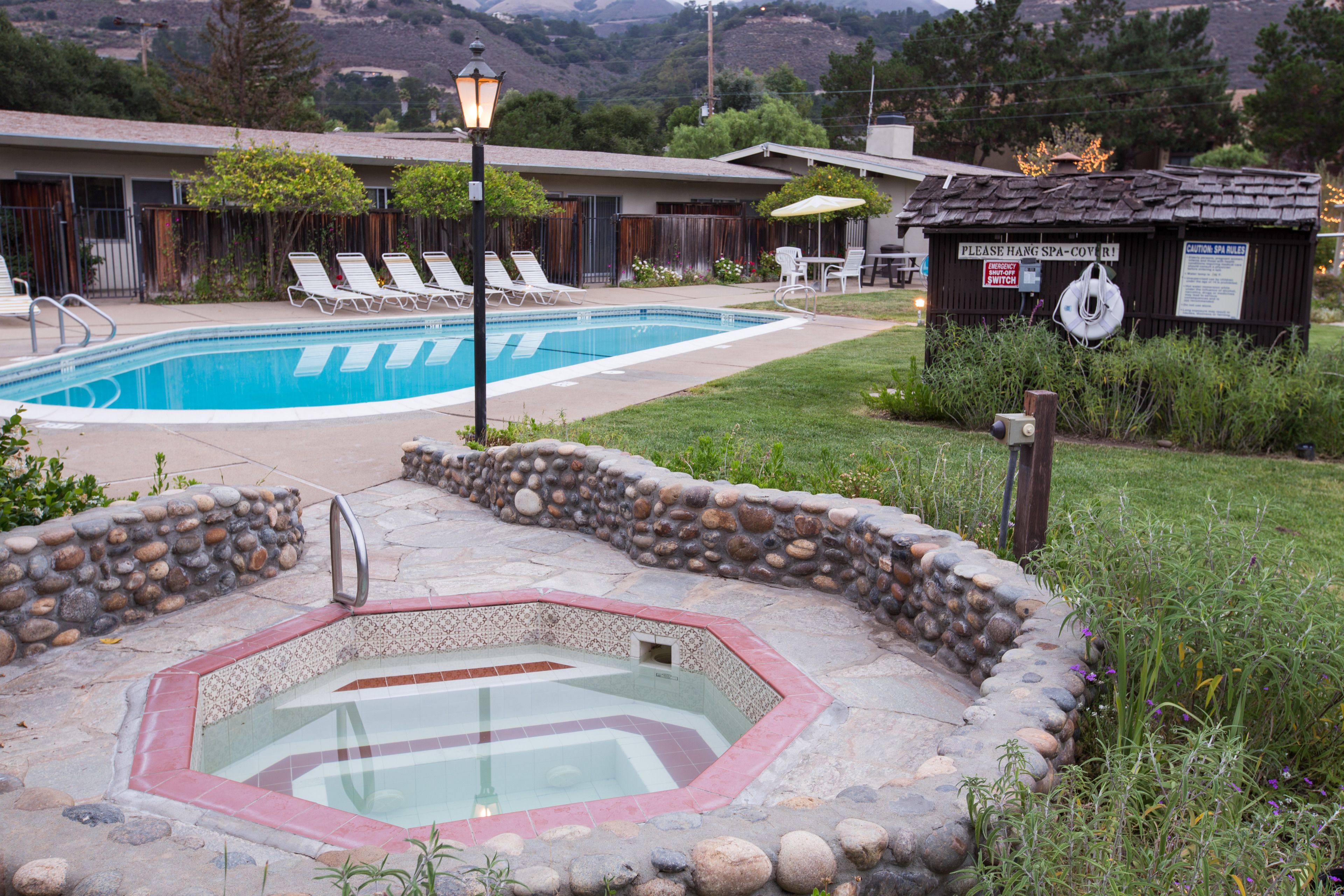 A swimming pool with lounge chairs, a hot tub, and a spa cover sign.