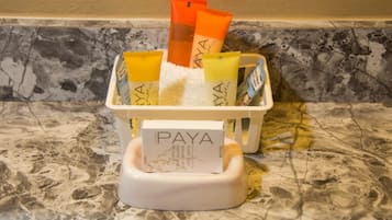 A bathroom counter with a white basin containing several tubes of Paya bath products.