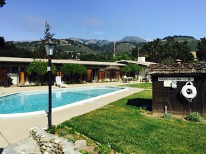 A pool area with a sign instructing to hang a spa cover, surrounded by a building with a view of mountains.