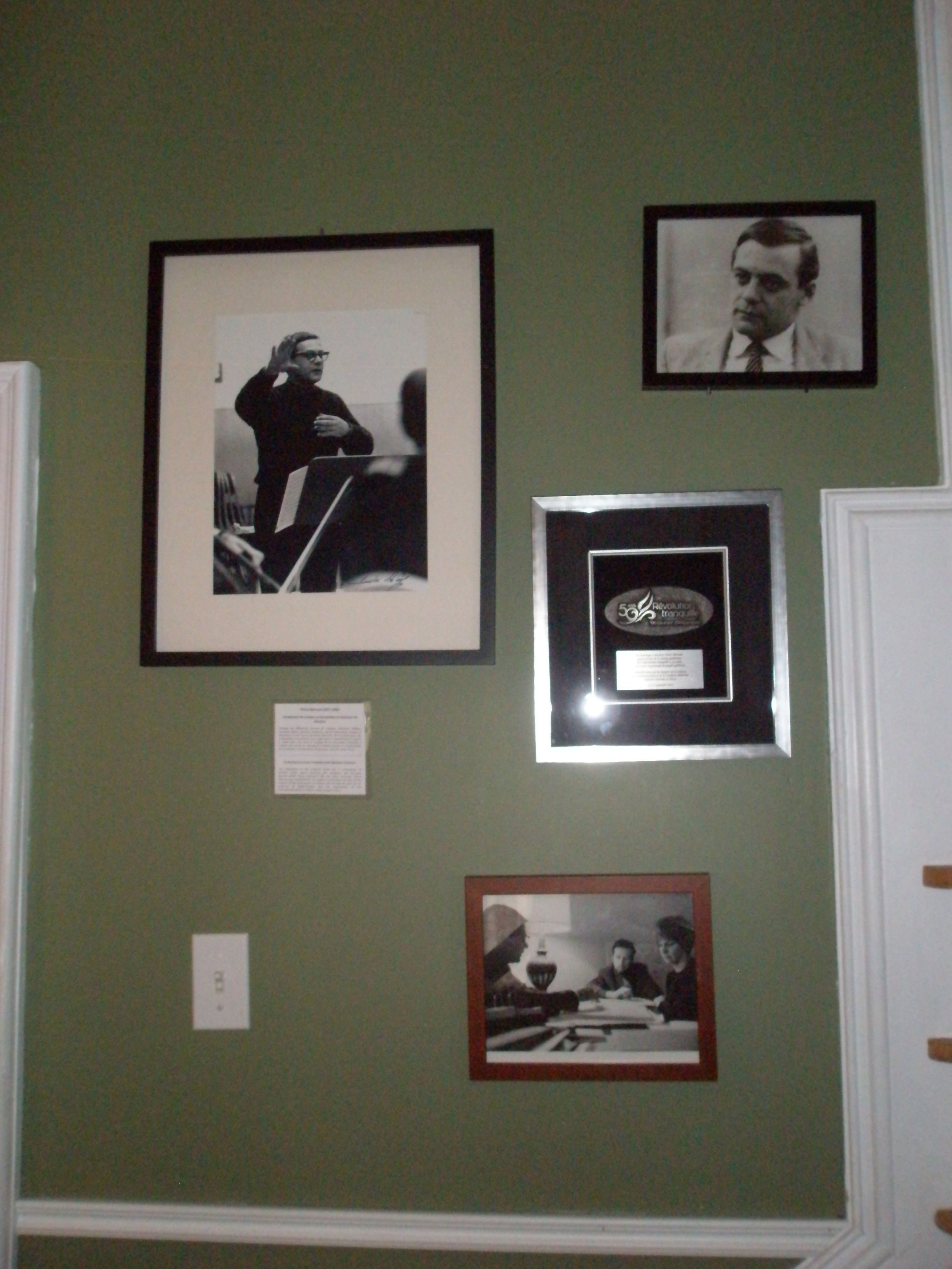 A wall with four framed photographs and a plaque.