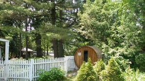 A rustic wooden cabin surrounded by lush greenery and a white picket fence.