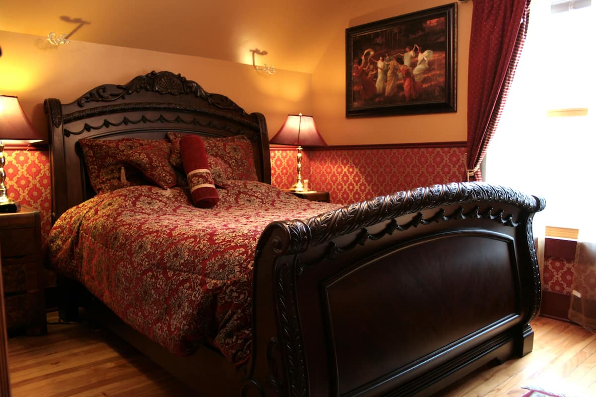 A bedroom with a large bed, ornate headboard, and patterned bedding.