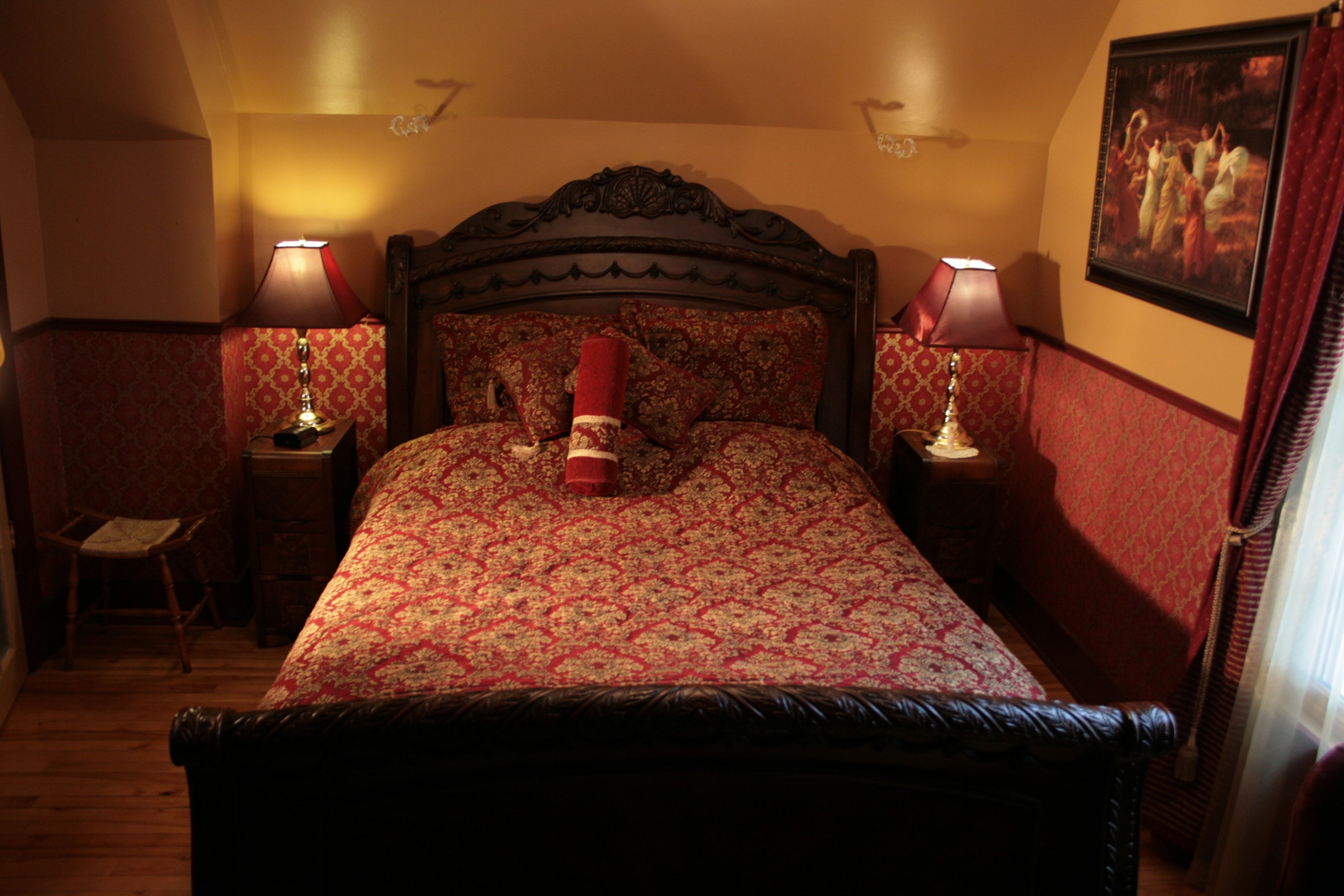 Een slaapkamer met een groot bed, twee nachtkastjes met lampen, een stoel en een schilderij aan de muur.