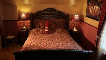 Een slaapkamer met een groot bed, twee nachtkastjes met lampen, een stoel en een schilderij aan de muur.