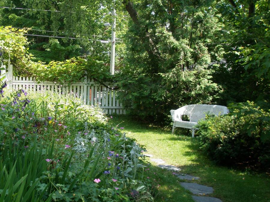 Un jardín con un banco blanco y un camino de piedra.