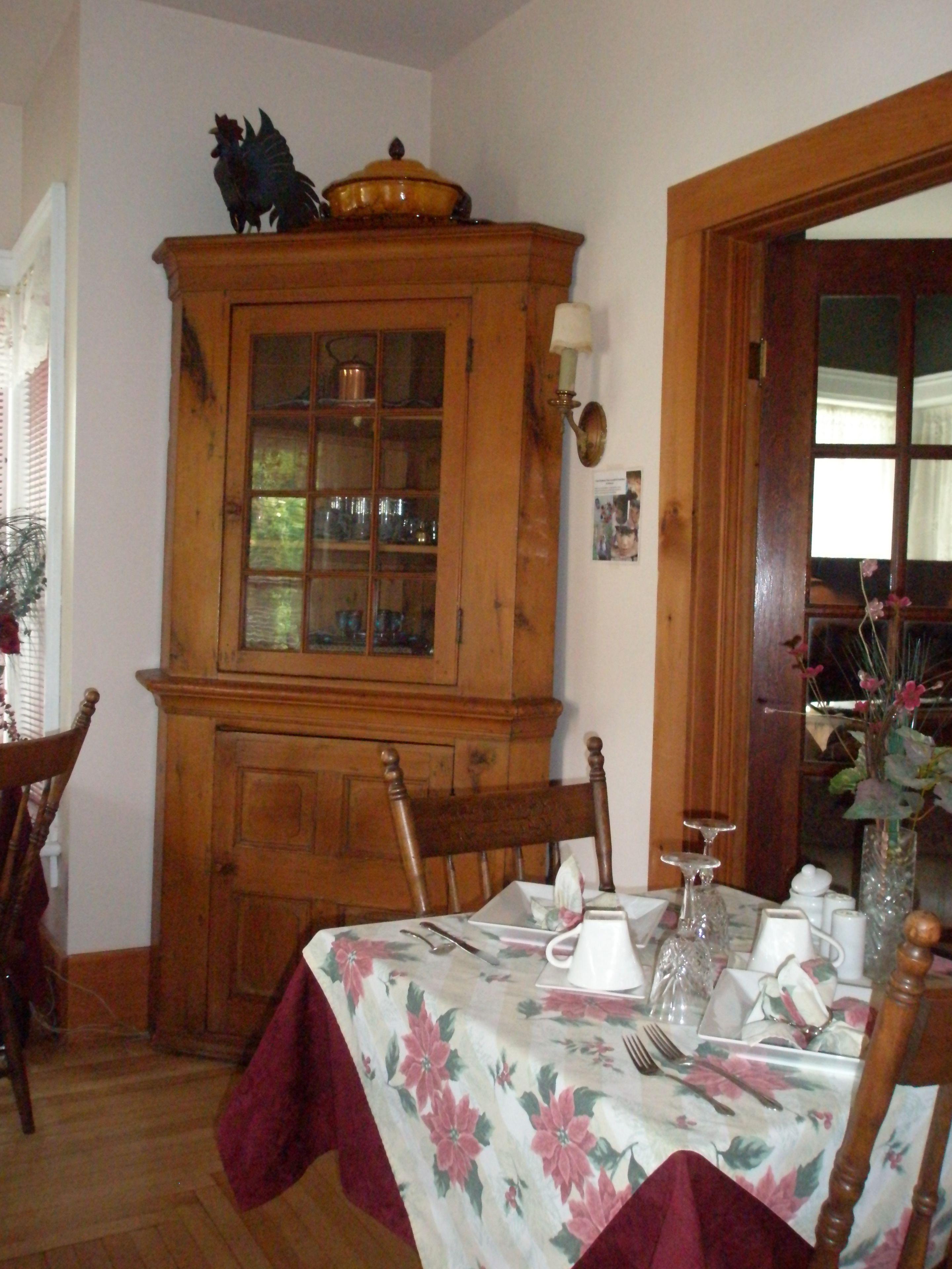 Ein Essbereich mit einem Holzschrank, einem Tisch mit floralem Tischläufer und Stühlen.