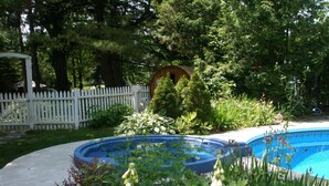 A swimming pool surrounded by lush greenery and a white picket fence.