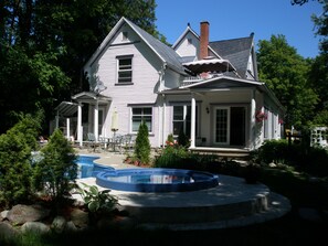 A two-story house with a large front porch, a swimming pool, and a well-maintained garden. - Ô Bois Dormant (Magog)