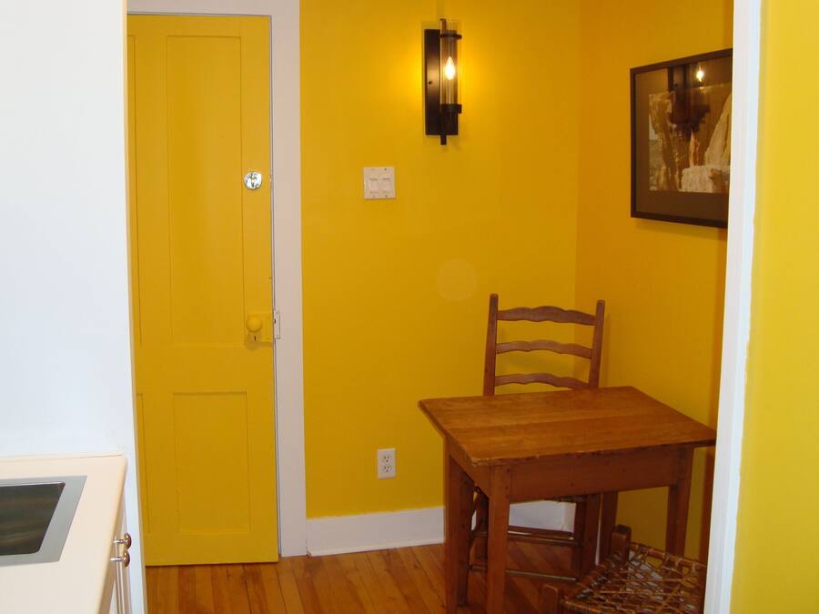 Una habitación con una pared amarilla, una mesa de madera y una silla.
