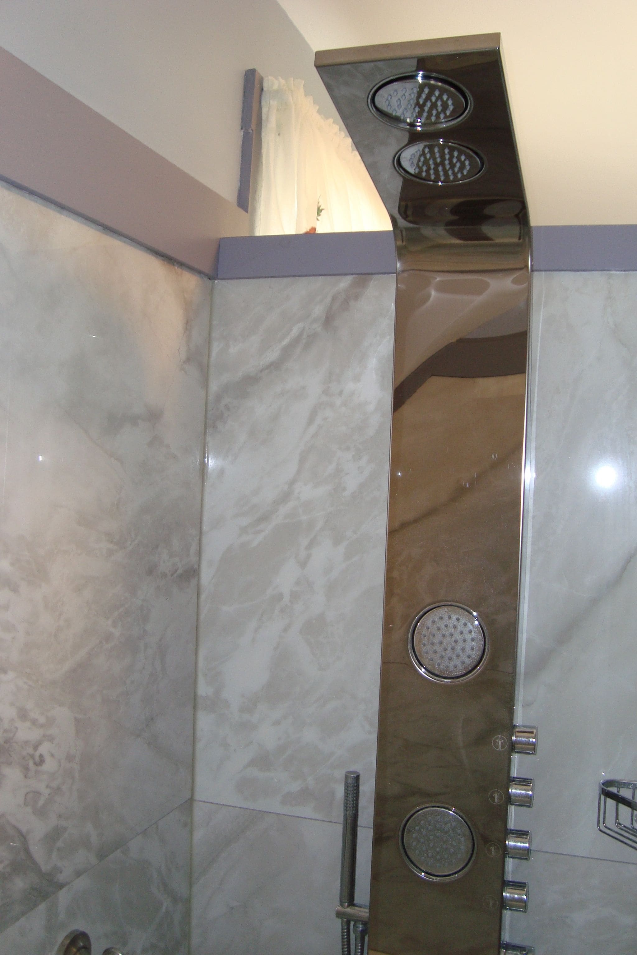 Un baño con cabina de ducha moderna, azulejos de mármol y un cabezal de ducha de acero inoxidable.