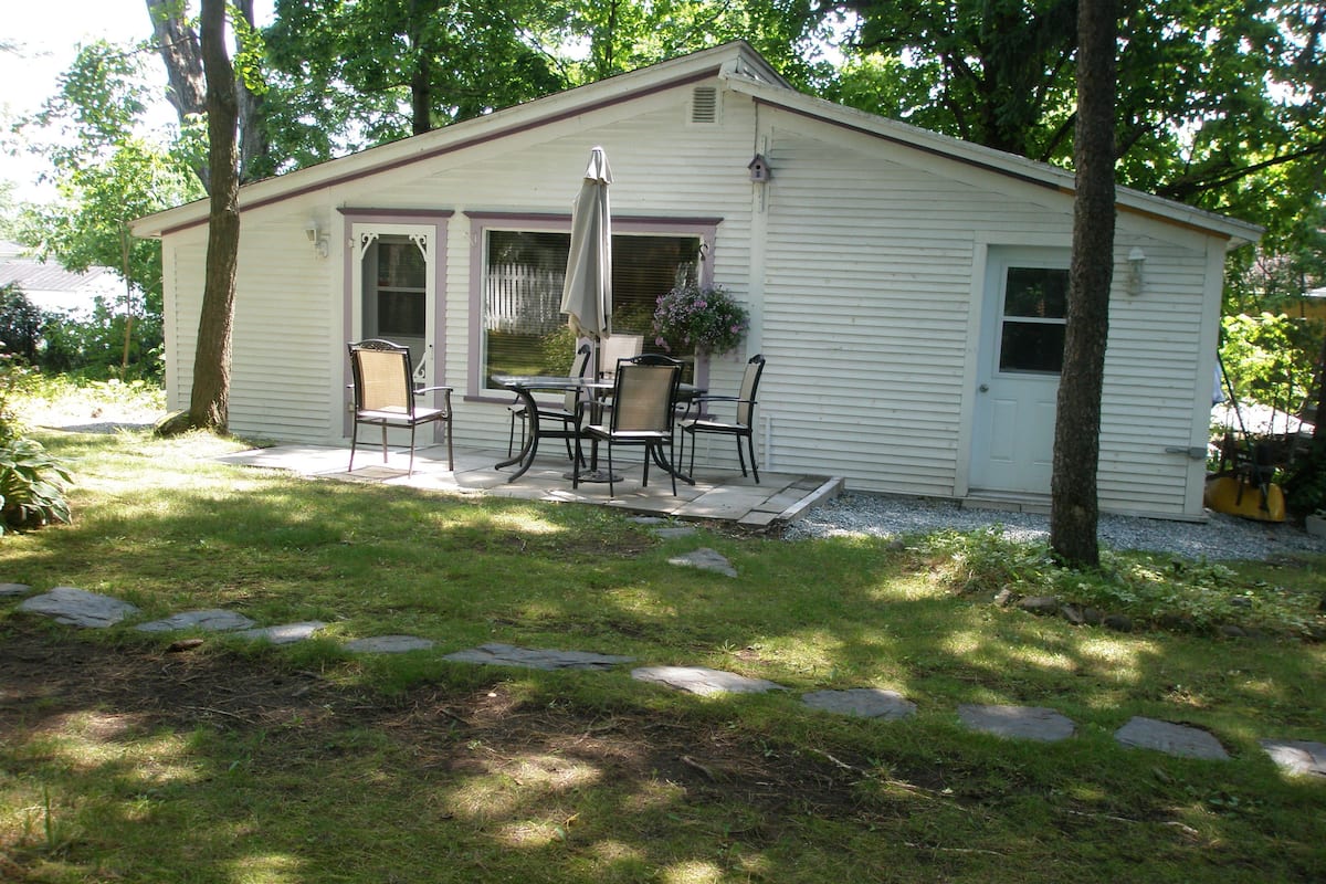 A small, single-story house with a patio area featuring a table and four chairs.