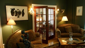 A living room with a sofa, a coffee table, and a lamp. There is a door leading to another room.