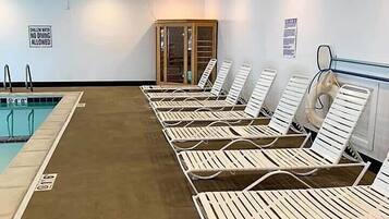 A swimming pool area with lounge chairs and a no diving allowed sign.