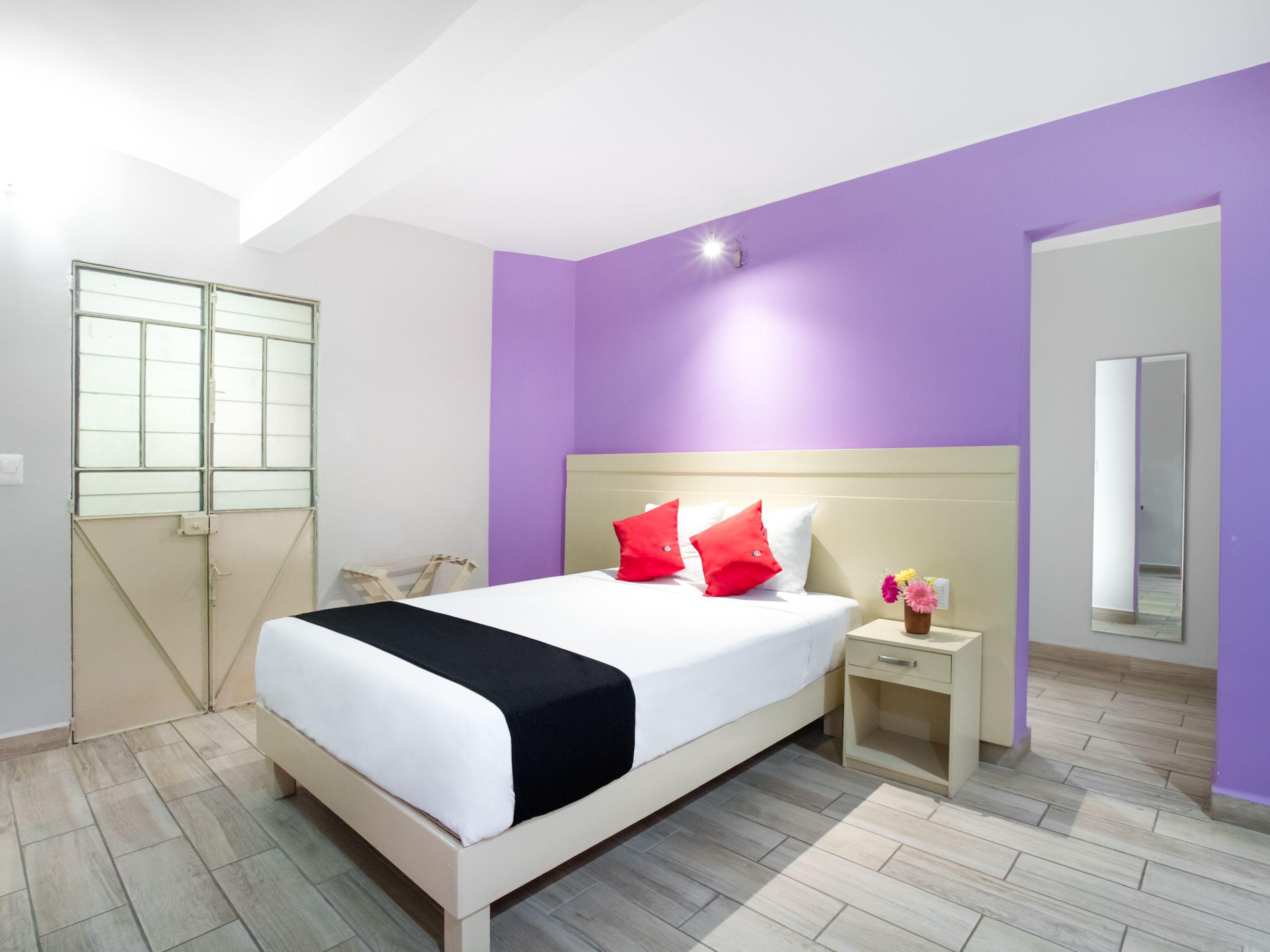 A modern bedroom with a bed, nightstand, and a mirror.