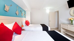 A hotel room with two beds, a TV mounted on the wall, and a desk with a vase of flowers. - Hotel El Andariego (Oaxaca)
